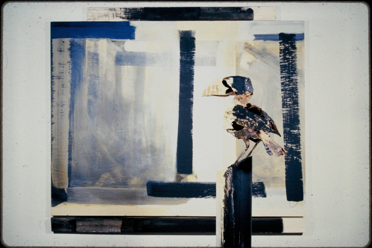 Wire-and-paper bird sculpture on a painted post in front of an abstract painting with black and blue bars.